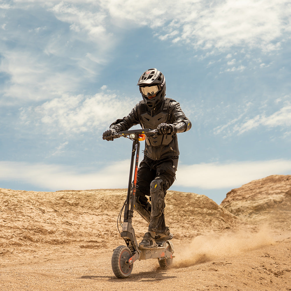 Riding the KuKirin G2 Ultra all-terrain electric scooter across a dusty desert trail.