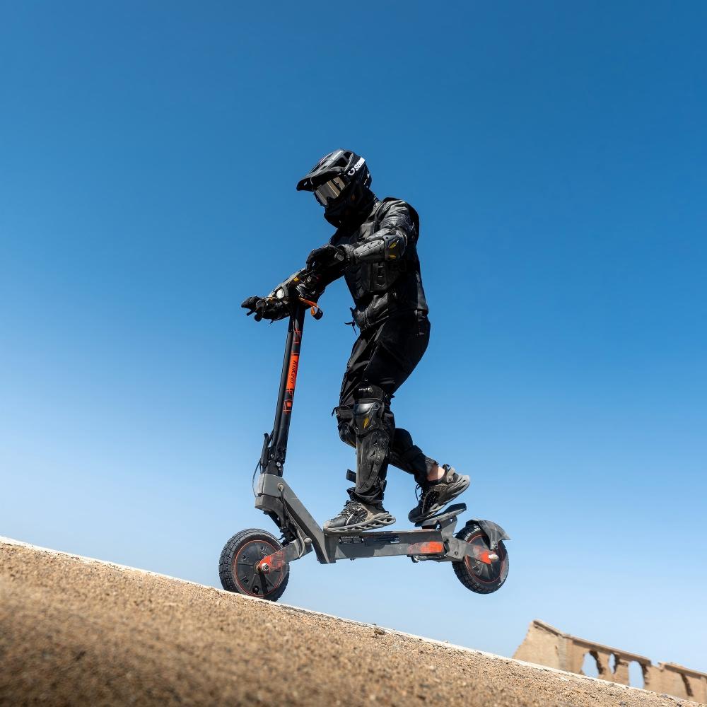 Rider getting airtime on the rugged KuKirin G2 Ultra electric scooter during a hill jump.